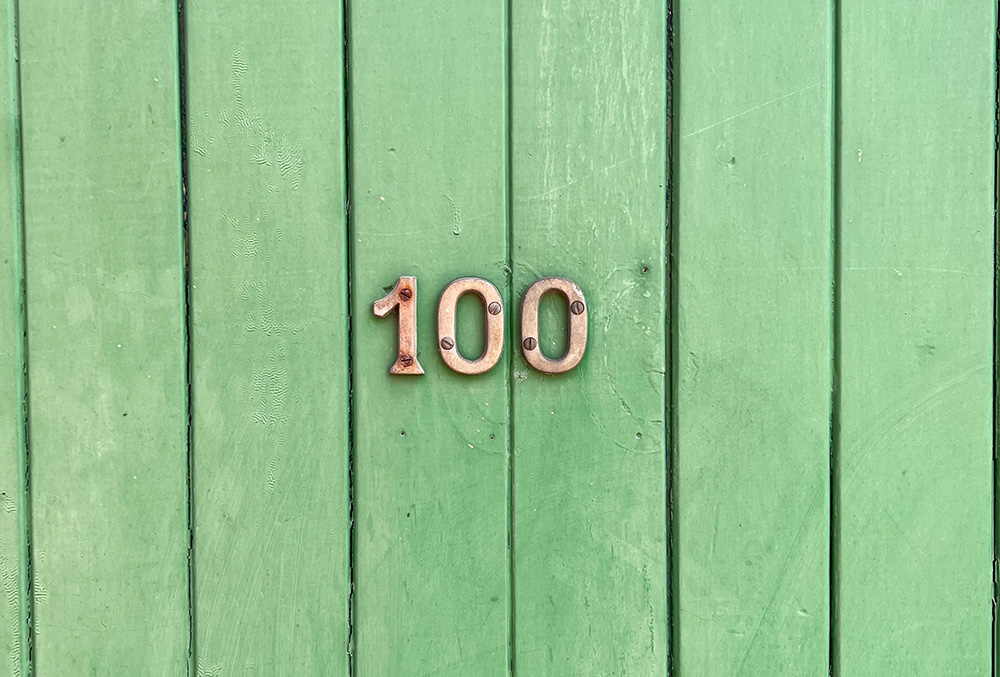 The number 100 on wood slats painted green (Unsplash/Tim Wildsmith)