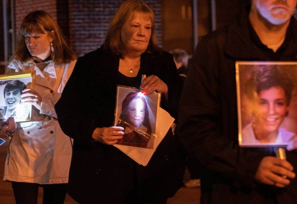 People hold photos of children at vigil for people abused by clergy