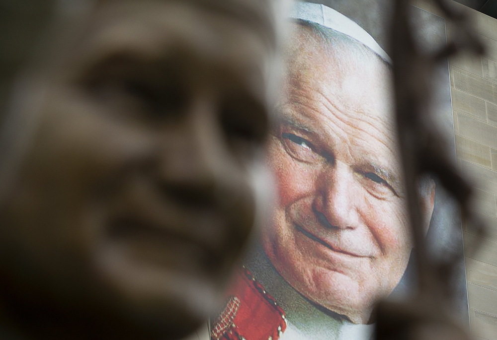 A banner of St. John Paul II is seen behind a sculpture of him May 16, 2018, at the St. John Paul II National Shrine in Washington. (CNS photo/Tyler Orsburn)