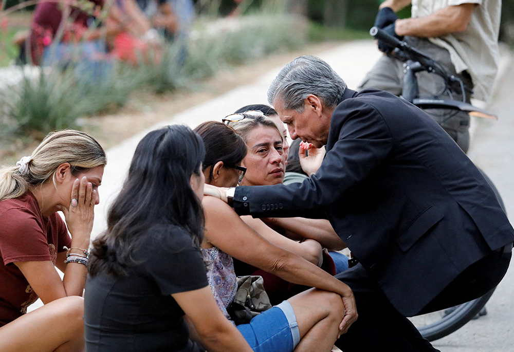 Archbishop Gustavo García-Siller of San Antonio comforts people outside the SSGT Willie de Leon Civic Center, where students had been transported from Robb Elementary School after a shooting May 24 in Uvalde, Texas. (CNS/Reuters/Marco Bello)