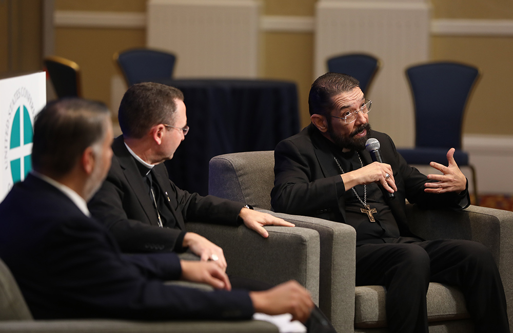 Bishop Daniel Flores of Brownsville, Texas, speaks during a news conference on the National Eucharistic Congress prior to a Nov. 16 session of the fall general assembly of the U.S. Conference of Catholic Bishops in Baltimore. Also pictured is Cande de Leon, chief advancement officer of the congress, and Bishop Andrew Cozzens of Crookston, Minnesota. (CNS/Bob Roller)