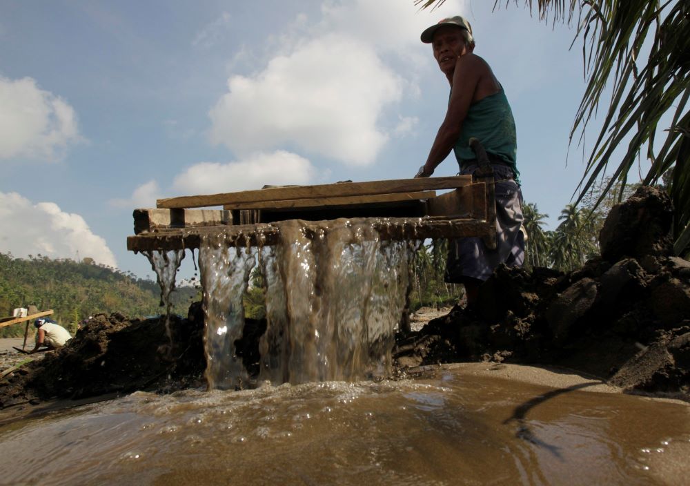 A small-scale miner is pictured in a file photo sifting for gold on a riverbed in Mawab, in the Mindanao region of Philippines. Large-scale mines also operate in the region, and four dioceses said lawmakers should draft another bill that would ultimately revoke the companies' licenses to preserve the ancestral lands of Indigenous peoples. (CNS/Reuters/Erik De Castro)