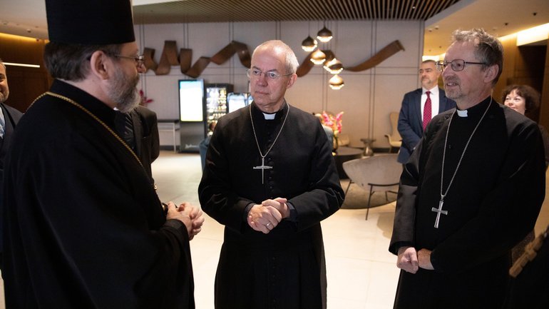 Three older white men clerics chat in an lobby