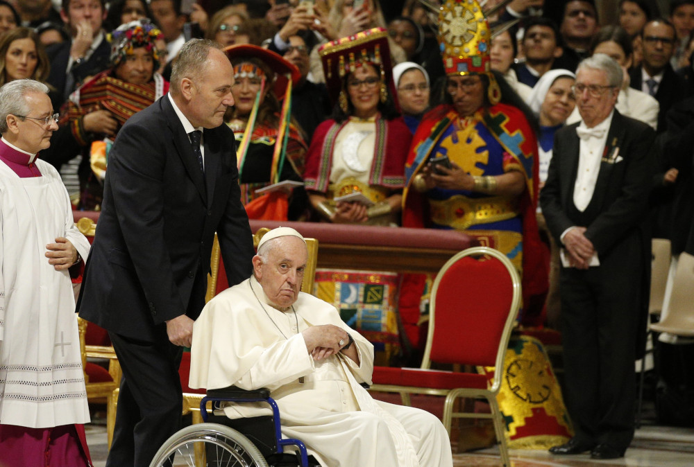 Pope Francis wheels by mass attendees in traditional attire