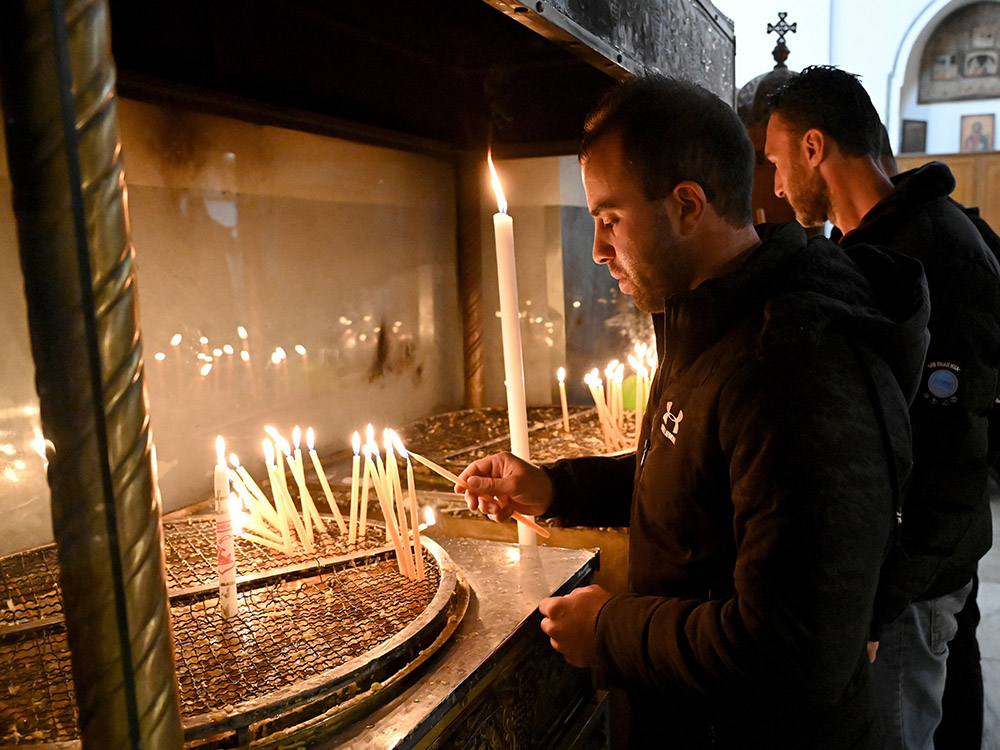 Palestinian Catholic Andrew Bannoura from Bethlehem lights a candle in the grotto of the Church of the Nativity in Bethlehem, West Bank, Dec. 15. (CNS/Debbie Hill)