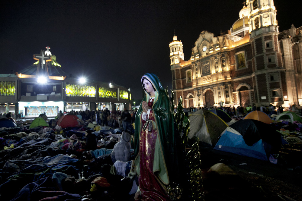 A statue of the Virgin of Guadalupe stands next to sleeping pilgrims as they wait for mass outside of the Basilica of Guadalupe in Mexico City, Dec. 12, 2015. (AP Photo/Marco Ugarte, File)