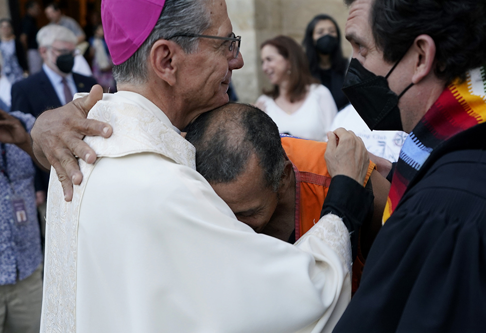 Jose Prin, center, a migrant from Venezuela, is greeted by Archbishop Gustavo García-Siller, left, after a multi-faith memorial Mass and prayer vigil at San Fernando Cathedral to honor the victims and survivors of the human smuggling tragedy, June 30 in San Antonio. More than 50 people died in the human-smuggling attempt. (AP photo/Eric Gay)