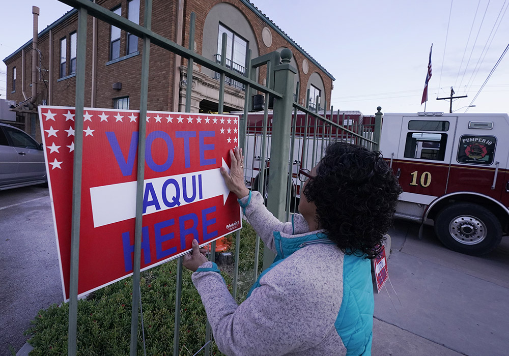 Election worker Ramona Ortiz places a sign outside a polling station at a fire station in El Paso, Texas, just before polls open on Nov. 8, 2022. (AP/LM Otero, File)