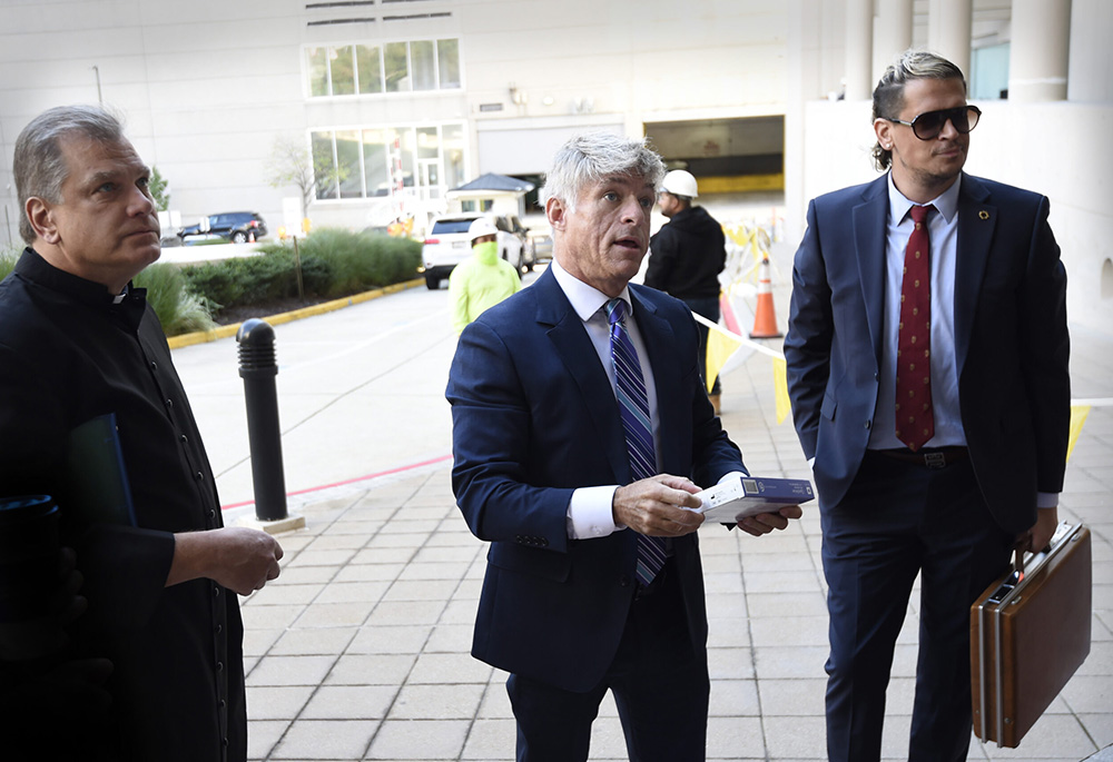 The Rev. Paul Kalchik, from left, St. Michael’s Media founder and CEO Michael Voris, center, and Milo Yiannopoulos talk with a court officer before entering the federal courthouse, Sept. 30, 2021, in Baltimore. A federal judge blocked Baltimore city officials from banning the conservative Roman Catholic media outlet from holding a prayer rally at a city-owned pavilion during a U.S. bishops’ meeting in November. (AP photo/Gail Burton, file)