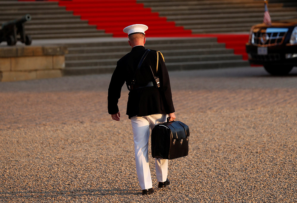 A U.S. military aide in Woodstock, Britain, carries the "football" containing launch codes for nuclear weapons into Blenheim Palace July 12, 2018, where former President Donald Trump and first lady Melania Trump were dining. (CNS/Reuters/Kevin Lamarque)
