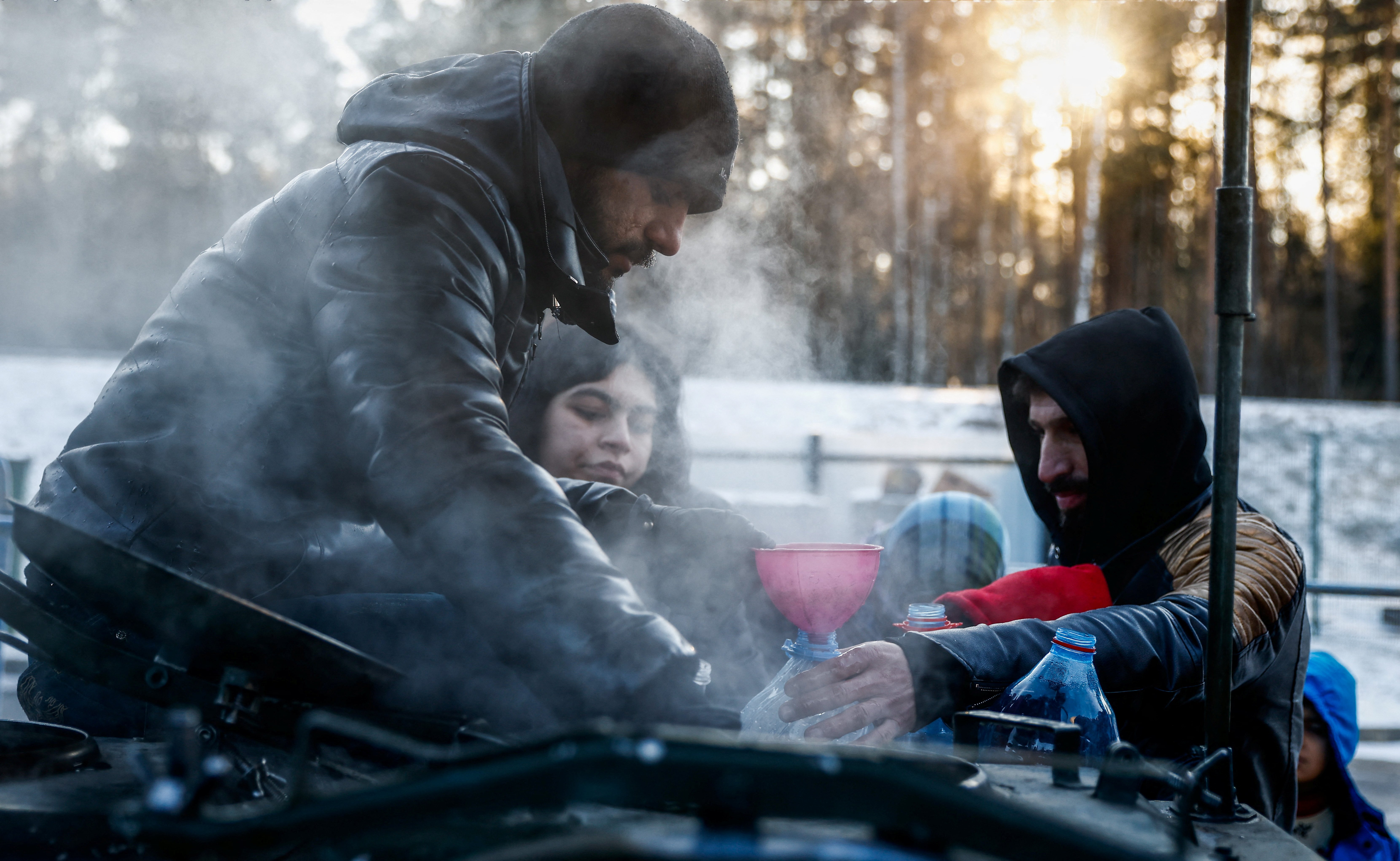 Migrants collect hot water outside the transport and logistics center, Bruzgi, on the Belarusian-Polish border, in the Grodno region of Belarus, in this Dec. 22, 2021. (CNS photo/Maxim Shemetov, Reuters)