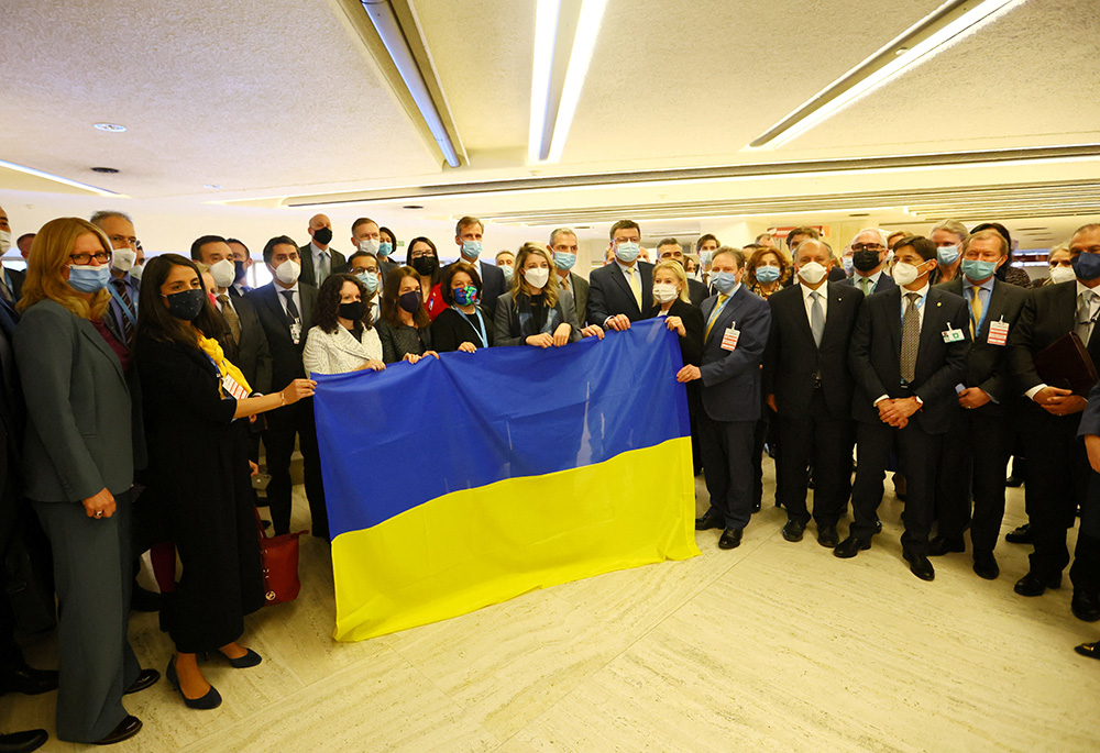 Mélanie Joly, Yevheniia Filipenko, Ukraine's permanent U.N. representative, and other delegates gather with a Ukrainian flag after walking out of the U.N. Human Rights Council meeting during a Russian video speech March 1 in Geneva. (CNS)
