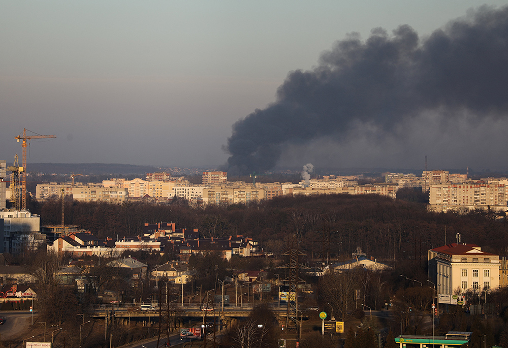 Smoke rises above buildings near the Lviv airport, as Russia's invasion of Ukraine continues, March 18 in Lviv, Ukraine. (CNS/Reuters/Roman Baluk)