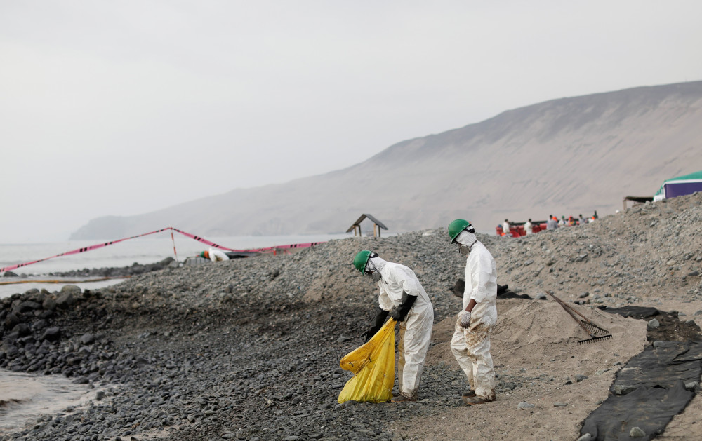 Workers clean up an oil spill on the beach near Repsol's La Pampilla refinery that caused an ecological disaster on the coasts of Lima, in Ventanilla, Peru, in this Jan. 29, 2022. (CNS/Reuters/Angela Ponce)