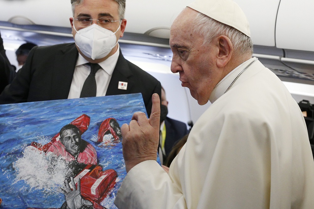 Pope Francis gestures as he looks at artwork presented by a journalist on his flight from Rome to Malta April 2, 2022.