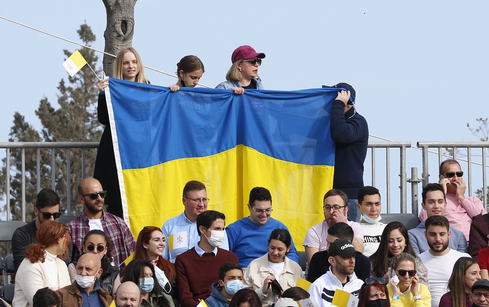 People hold the Ukrainian flag as they wait for the start of Pope Francis' celebration of Mass at the Granaries in Floriana, Malta, April 3, 2022.