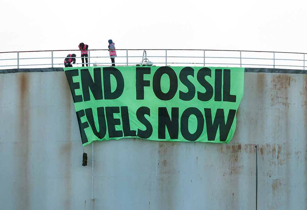 Activists at Esso West London Terminal in Staines, England, hang a sign on a storage tank April 1. (CNS/Reuters/John Sibley)