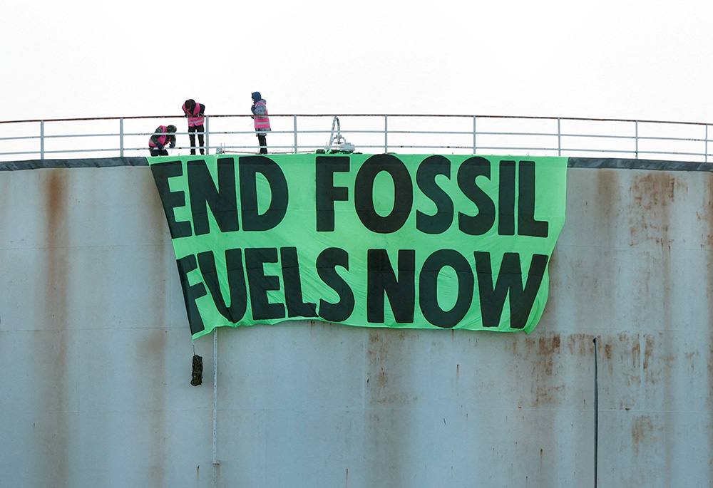Activists at Esso West London Terminal in Staines, England, hang a sign on a storage tank April 1. (CNS/Reuters/John Sibley) Activists at Esso West London Terminal in Staines, England, hang a sign on a storage tank April 1. (CNS/Reuters/John Sibley)