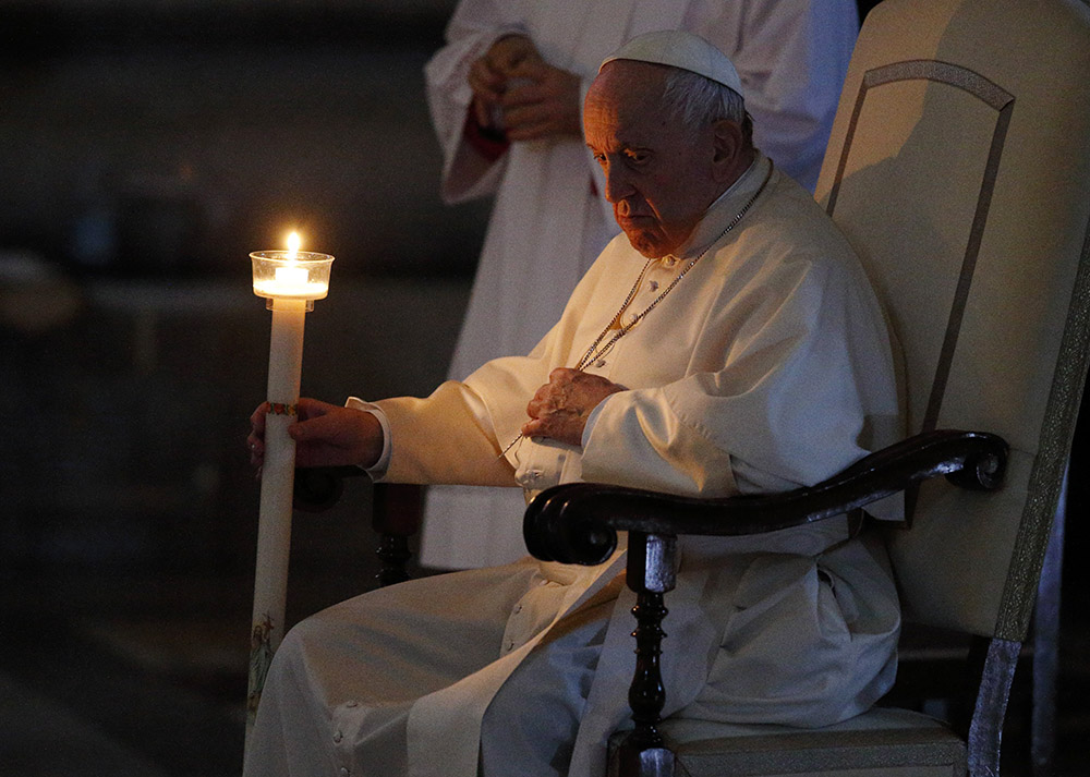 Pope Francis holds a candle as he attends the Easter Vigil celebrated by Cardinal Giovanni Battista Re in St. Peter's Basilica at the Vatican April 16. (CNS/Paul Haring)