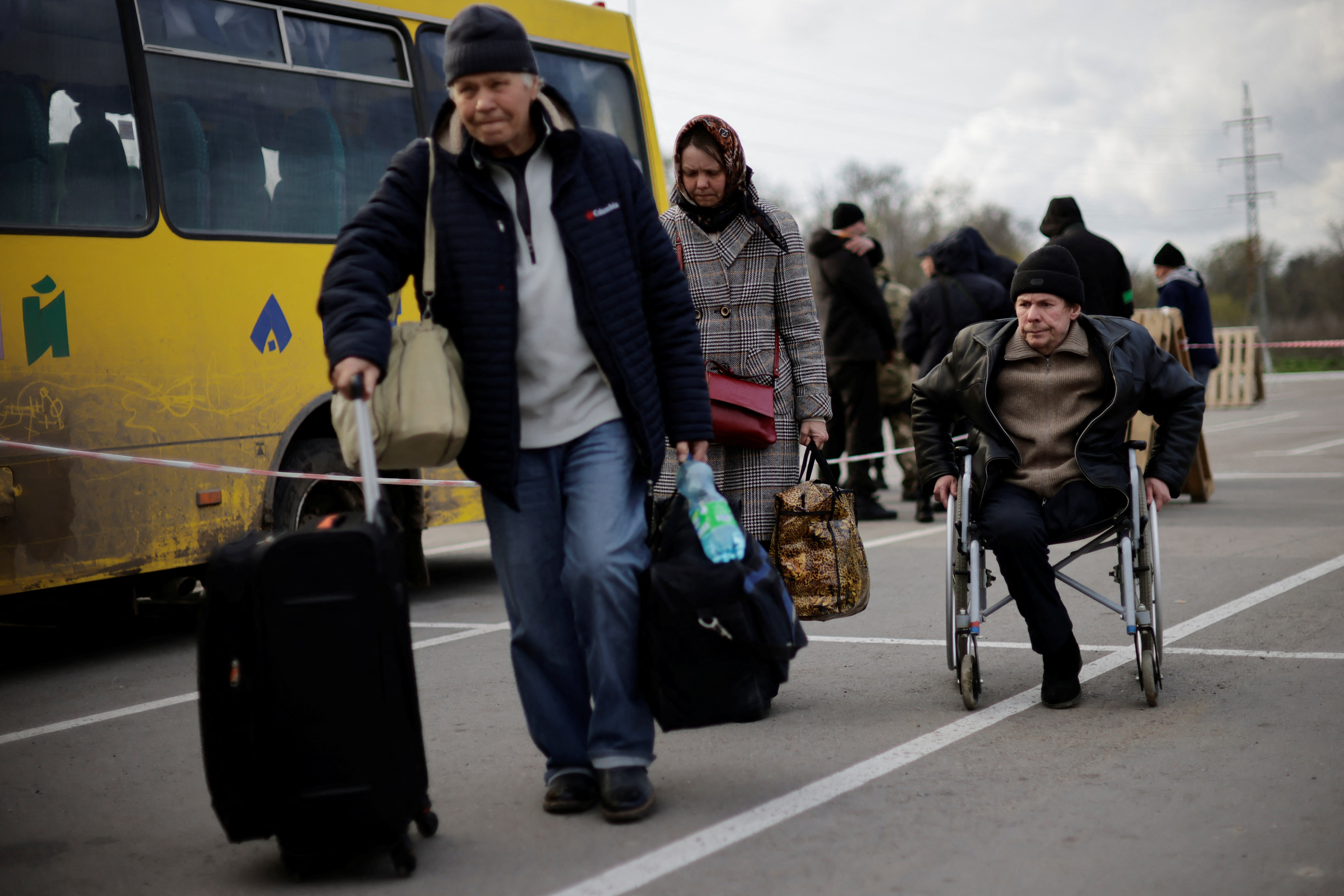 Ukrainian refugees in Zaporizhzhia, Ukraine, walk towards a registration center for internally displaced people April 21, 2022, after arriving in a small convoy that crossed through a territory held by Russian forces. (CNS photo/Ueslei Marcelino, Reuters)