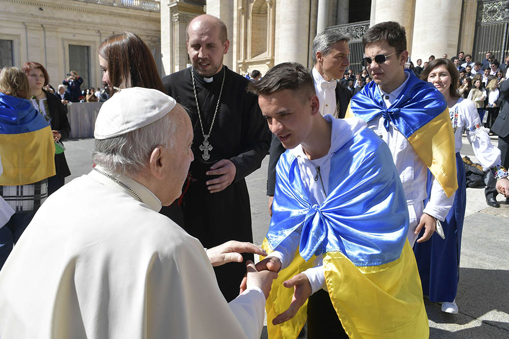 Pope Francis greets a man draped in a Ukrainian flag after his weekly general audience in St. Peter's Square at the Vatican April 27, 2022. In the group were 11 orphaned children who escaped Ukraine.
