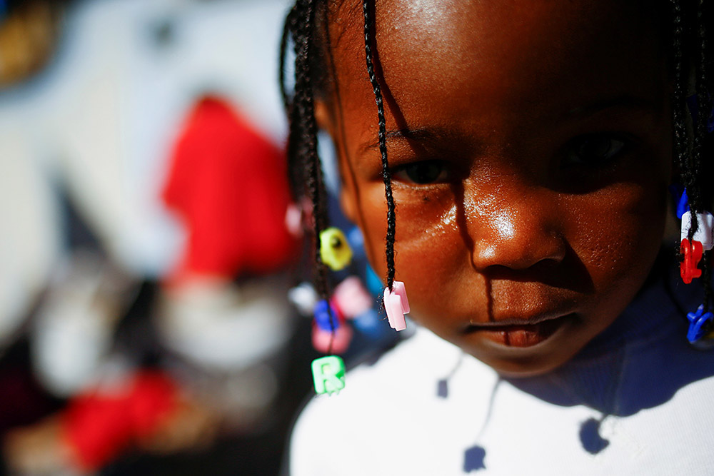 A young Haitian migrant girl traveling with her parents, seeking to reach the U.S., stands outside a temporary shelter at a church in Ciudad Juárez, Mexico, Dec. 20, 2021. (CNS/Reuters/Jose Luis Gonzalez)