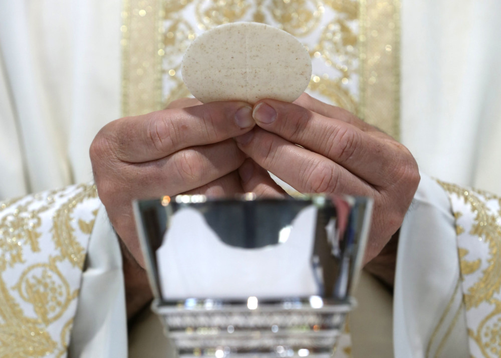 A priest holds the Eucharist in this illustration taken May 27, 2021. (CNS/Bob Roller)