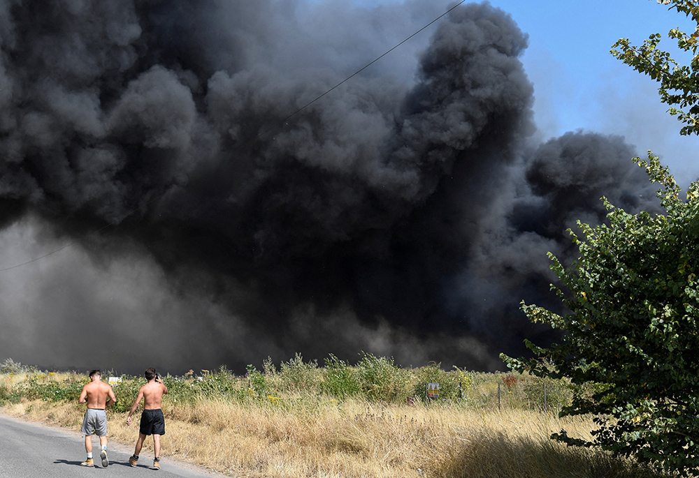 People watch as a fire burns during a heatwave July 19 in London. London's fire service had its busiest day since World War II dealing with several blazes in record-breaking temperatures, London Mayor Sadiq Khan said. (CNS/Reuters/Tony O'Brien) People watch as a fire burns during a heatwave July 19 in London. London's fire service had its busiest day since World War II dealing with several blazes in record-breaking temperatures, London Mayor Sadiq Khan said. (CNS/Reuters/Tony O'Brien)