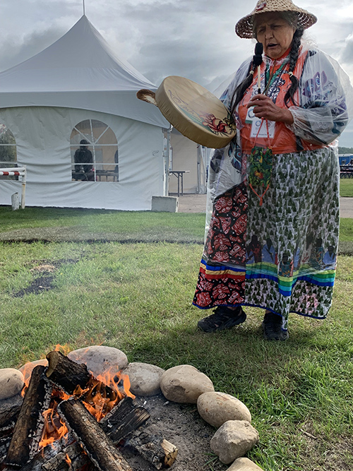 Ruby Rose Henry, a member of the Tla'amin Nation, warms up by a fire before Pope Francis arrives at the Muskwa, or Bear Park, Pow-Wow Grounds July 25 in Maskwacis, Alberta. (CNS/Cindy Wooden)