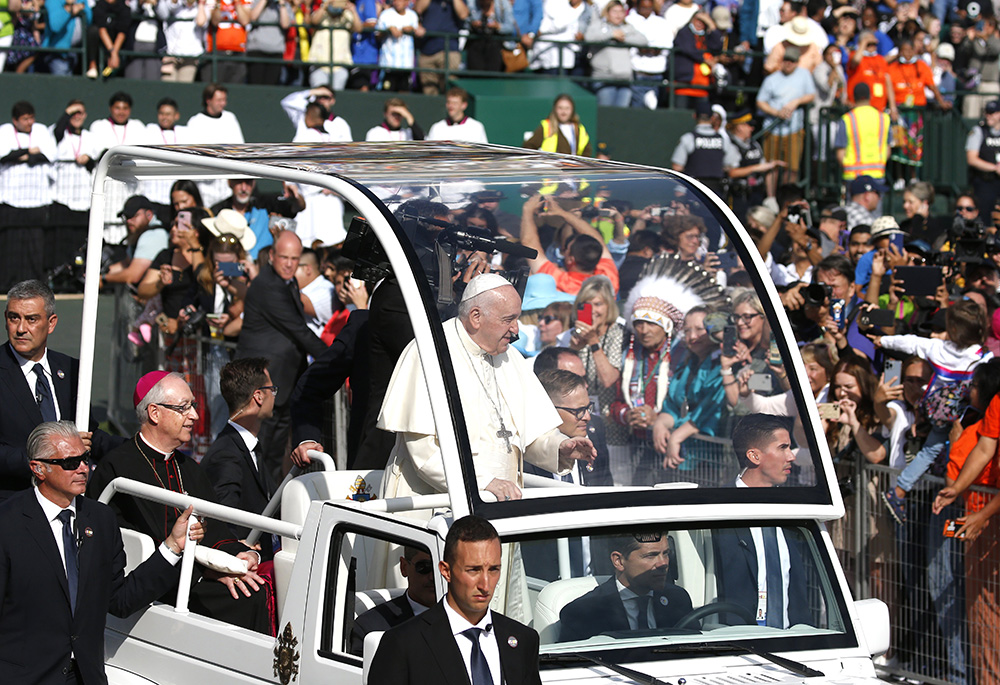 Pope Francis arrives to celebrate Mass at Commonwealth Stadium July 26 in Edmonton, Alberta, Canada. Looking on in the background with headdress is Phil Fontaine, former national chief of the Assembly of First Nations. (CNS/Paul Haring) Pope Francis arrives to celebrate Mass at Commonwealth Stadium July 26 in Edmonton, Alberta, Canada. Looking on in the background with headdress is Phil Fontaine, former national chief of the Assembly of First Nations. (CNS/Paul Haring)