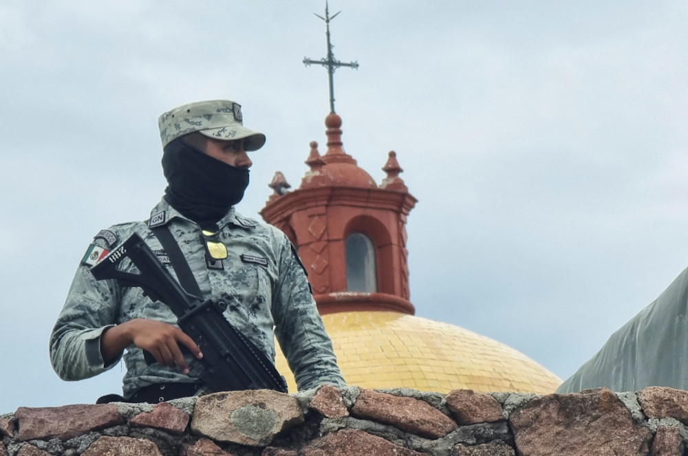A member of the Mexican army stands guard outside a church in the parish community of Cerocahui June 22. (CNS/Reuters)