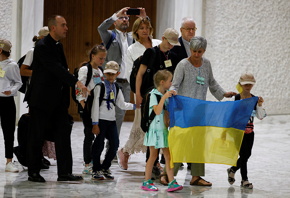 Ukrainian refugees, carrying a Ukrainian flag, attend Pope Francis' weekly general audience Aug. 24 at the Vatican. (CNS/Reuters/Guglielmo Mangiapane)