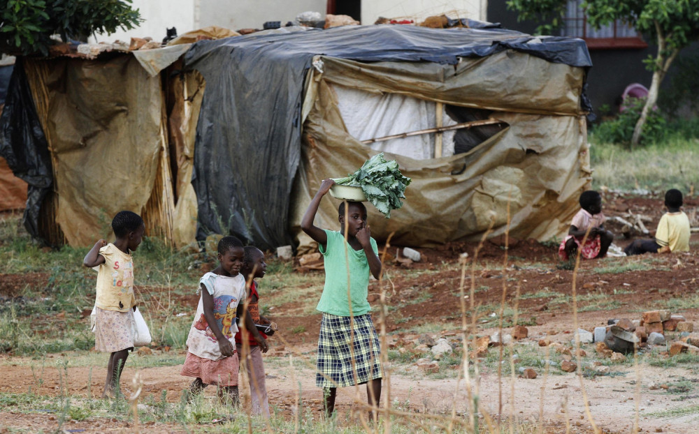 Zimbabwean children are pictured in a file photo carrying vegetables as they walk past a house in Harare