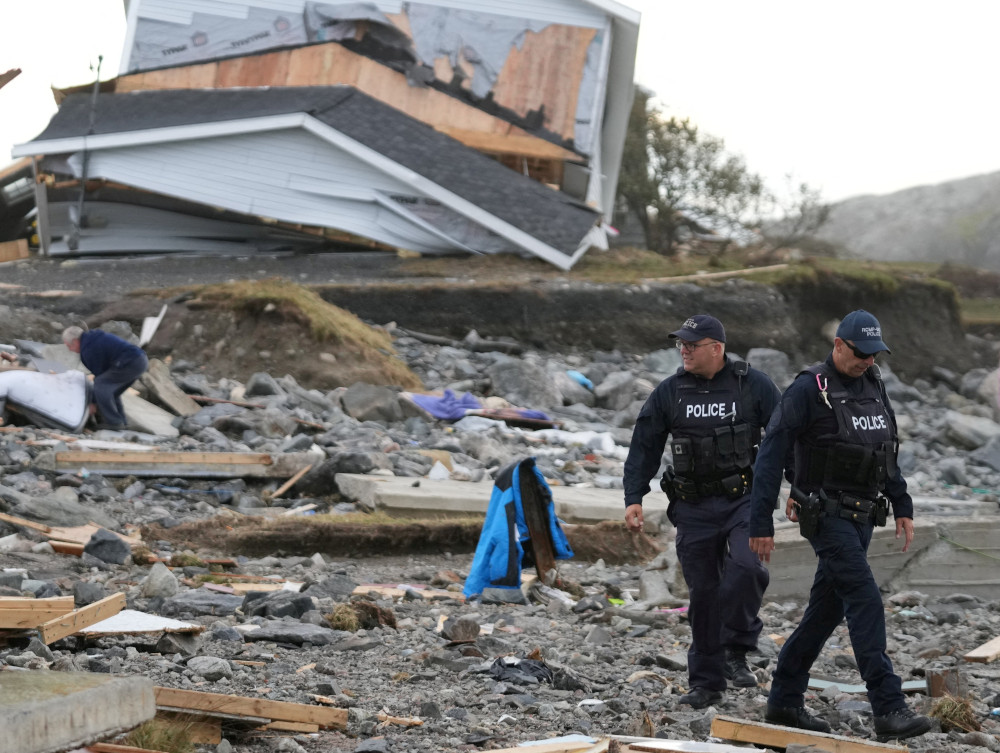 Police officers walk near a destroyed home along the coastline in Port Aux Basques, Newfoundland, Sept. 25, 2022. (CNS photo/John Morris, Reuters)