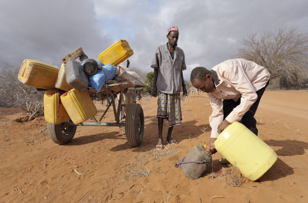 Adow Ibrahim Ali, right, is pictured in a file photo providing water to Ibrahim Osman Mohammed in a remote section of eastern Kenya near the Somali border