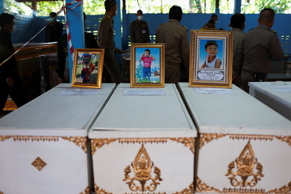 Pictures of victims stand on top of their caskets at Sri Uthai temple in Na Klang, Thailand, Oct. 7, 2022, following a mass shooting in Uthai Sawan