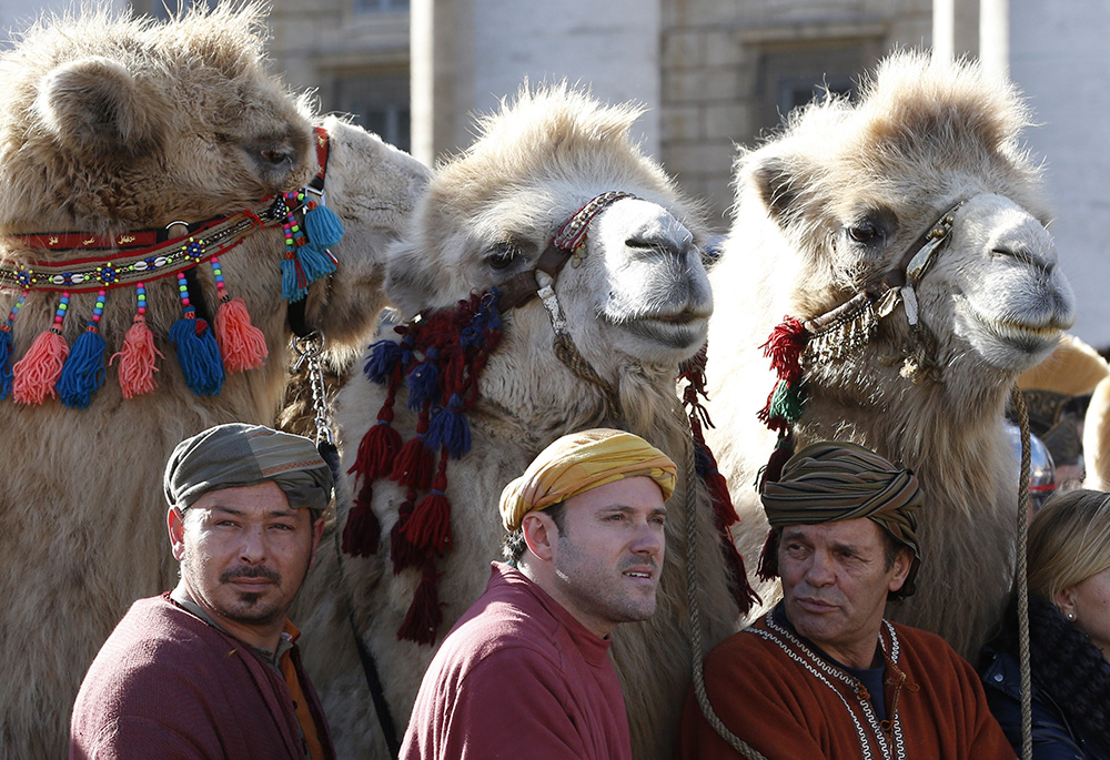 Three camels stand behind men in traditional attire in St. Peter's Square as Pope Francis leads the Angelus on the feast of the Epiphany in 2018 at the Vatican. (CNS/Paul Haring)