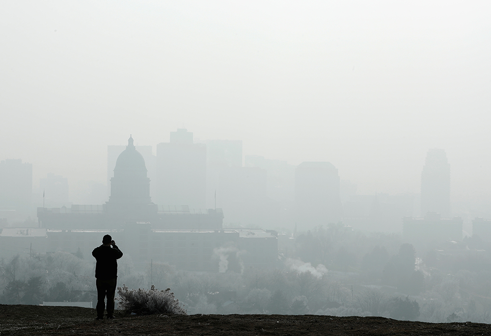 A man stops to take a picture of the Utah State Capitol and buildings that are shrouded in smog Dec. 12, 2017, in downtown Salt Lake City. (CNS/Reuters/George Frey)