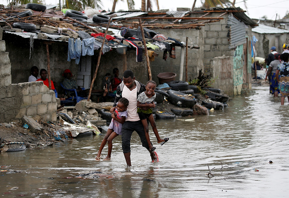 A man carries his children through floodwaters in the aftermath of Cyclone Idai, March 23, 2019, in Beira, Mozambique. More than 2 million people in Mozambique, Zimbabwe and Malawi were affected by a cyclone that killed more than 700 people, with hundreds still missing in Mozambique and Zimbabwe. (CNS/Reuters/Siphiwe Sibeko)