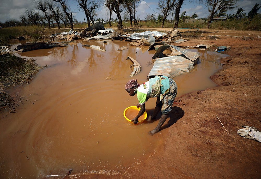 A woman collects water for washing as floodwaters begin to recede in the aftermath of a 2019 cyclone near Beira, Mozambique. (CNS/Reuters/Mike Hutchings)