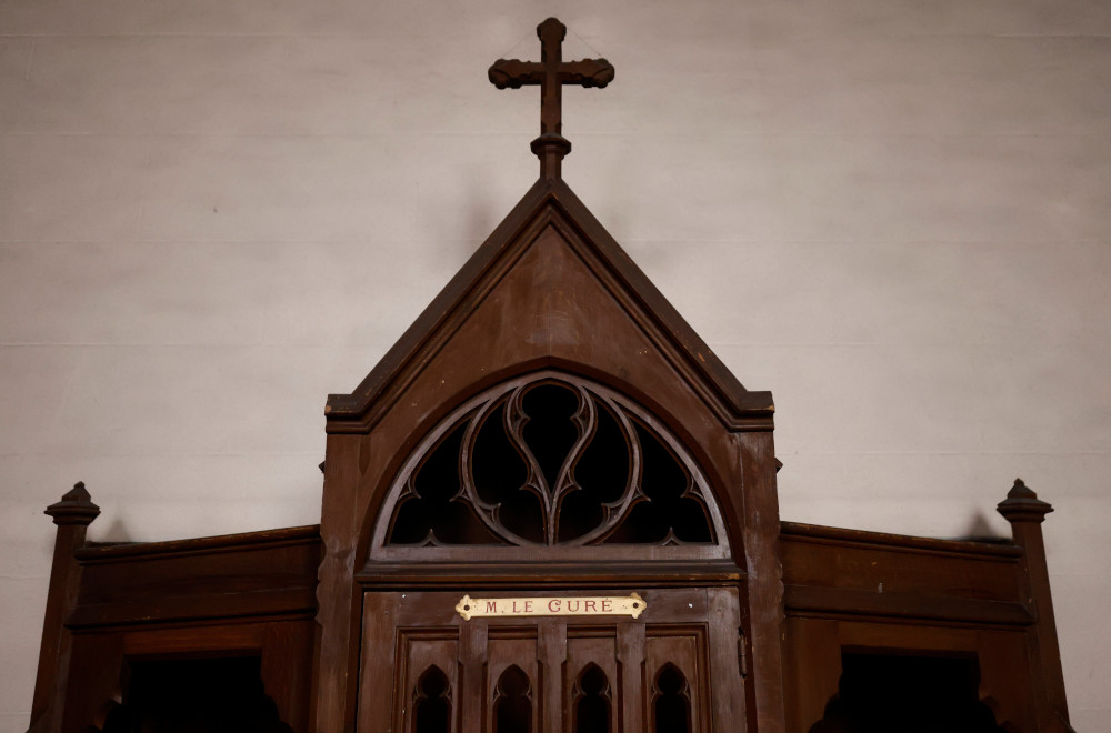 A brown confessional with a cross on the top