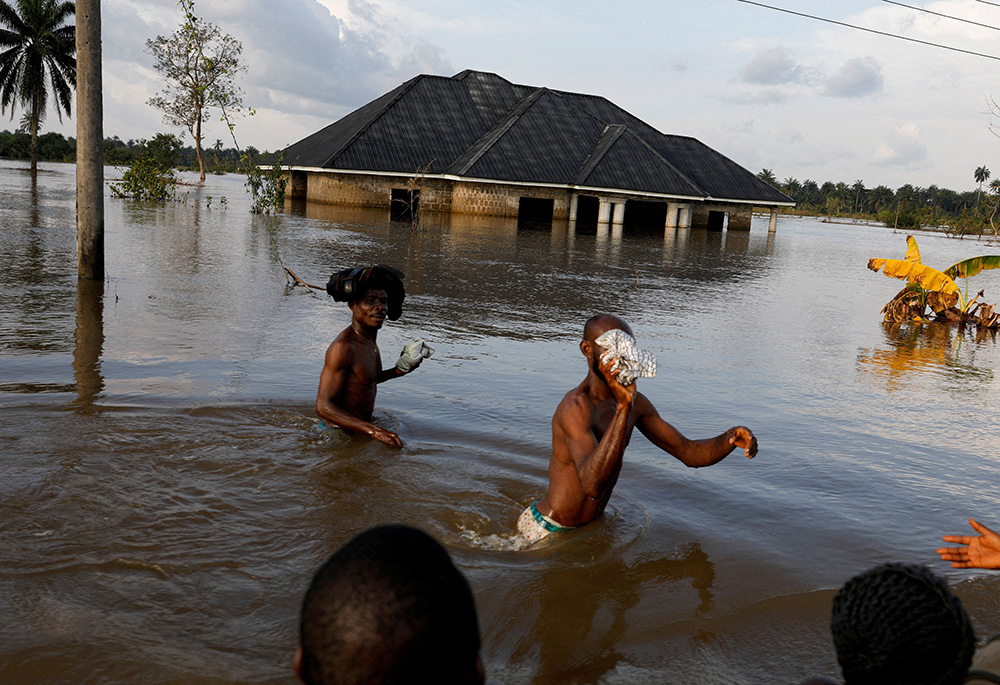 Residents wade through floodwater Oct. 22, 2022, in Ahoada, Nigeria. (CNS/Reuters/Temilade Adelaja)
