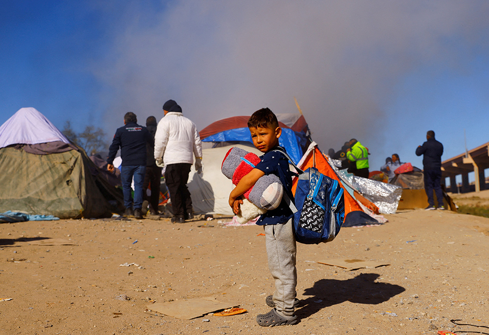 A child in Ciudad Juárez, Mexico, stands as police remove Venezuelan migrants from a camp on the banks of the Rio Grande Nov. 27, 2022. (CNS/Reuters/Jose Luis Gonzalez)