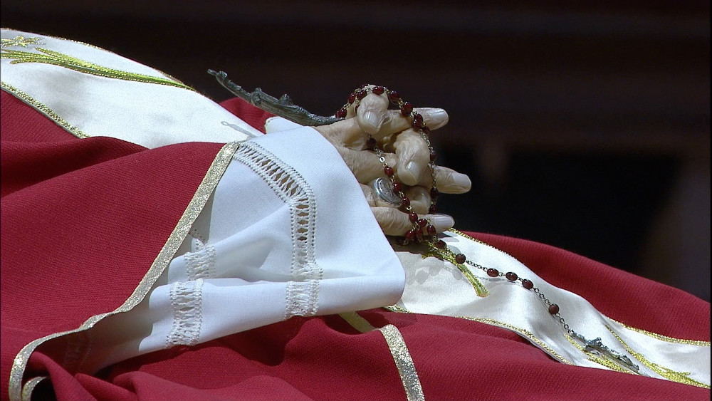 Pope Benedict XVI's folded hands have a ring on one finger and hold a rosary