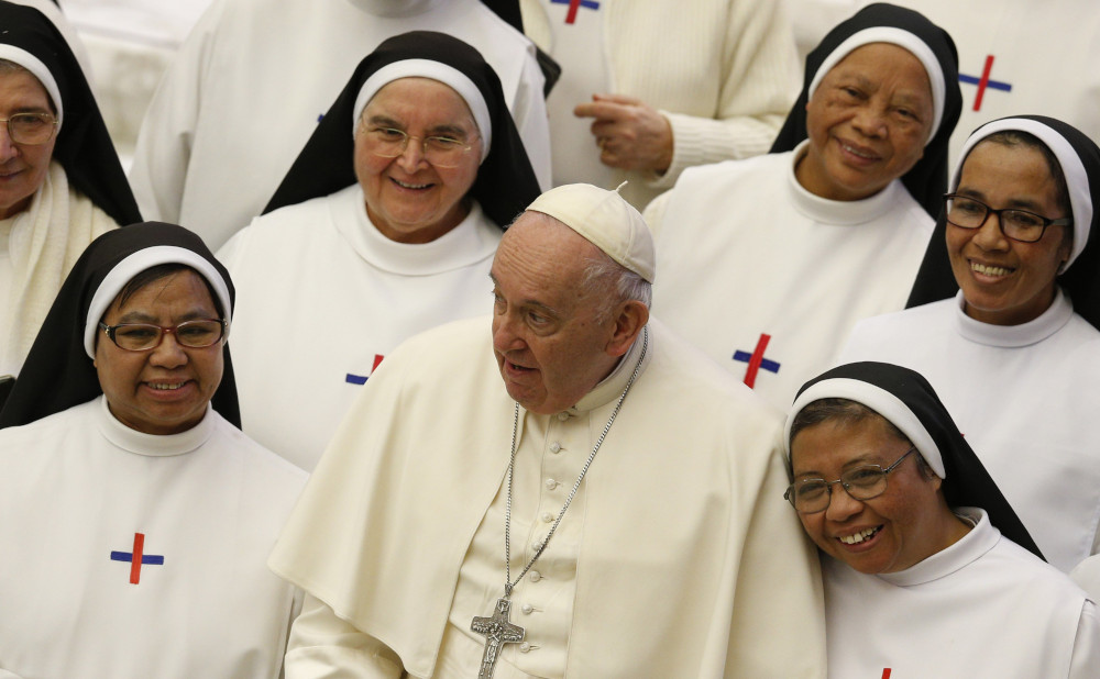 Pope Francis is surrounded by religious women of color wearing black and white