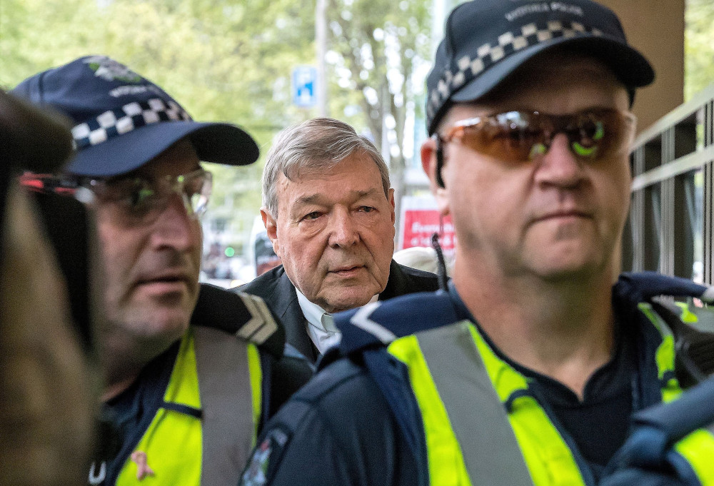 Australian Cardinal George Pell is seen in a 2017 file photo being escorted by police to the Melbourne Magistrates Court. (OSV News/Reuters/Mark Dadswell)