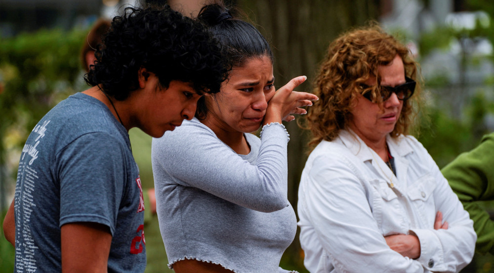 A Brown-skinned young woman, boy, and middle-aged woman look emotional. The young woman wipes a tear.
