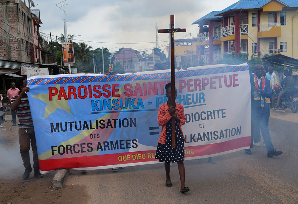 A young woman carries a cross during a march in Kinshasa, Democratic Republic of Congo, to protest escalating violence in the country, Dec. 4, 2022. (CNS/Reuters/Justin Makangara)