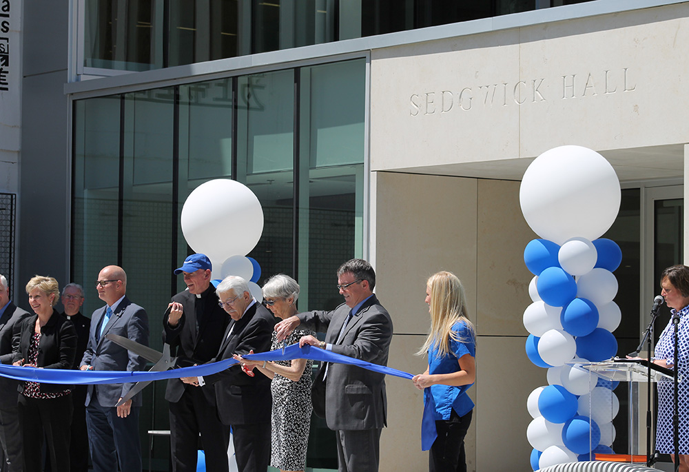 Jesuit Fr. Thomas Curran, center, then-president at Rockhurst University, cuts a ribbon at a ceremony dedicating the renovated Sedgwick Hall on June 3, 2022, in Kansas City, Missouri. (NCR photo/Brian Roewe)