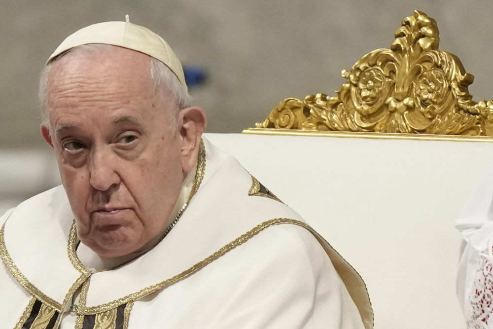 Pope Francis wears white and gold vestments and sits in a white and gold chair